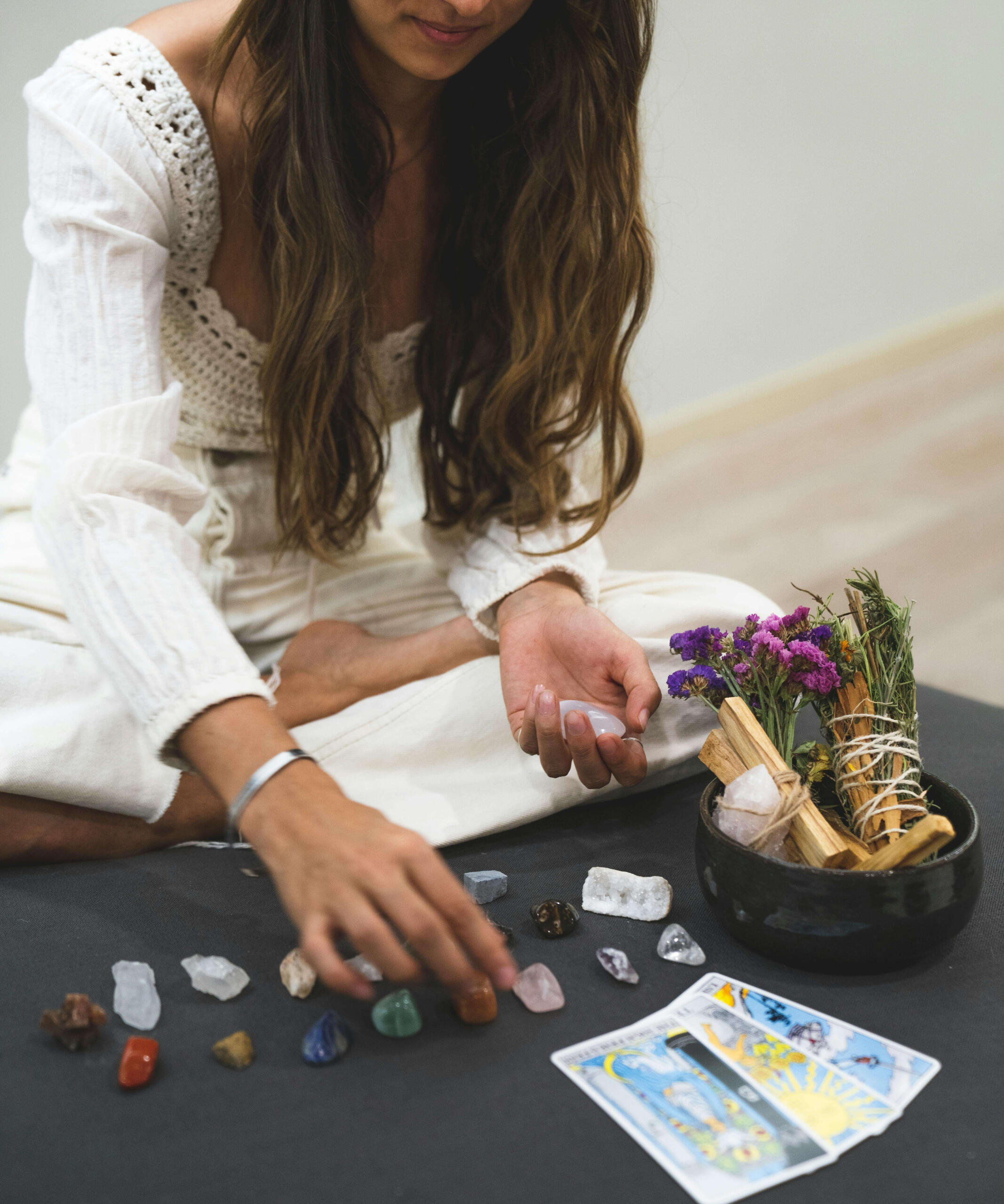 Crystal manifestation magic This is a photo of a woman holding a crystal and looking at some crystals, with tarot cards